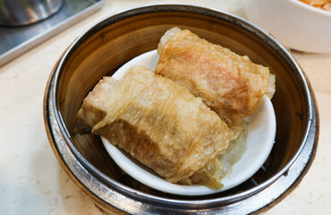 close up of Chinese Cantonese Dim Sum Steamed Chicken bean curd skin Roll with shrimp fish skin in a bamboo steamer container ordered in 