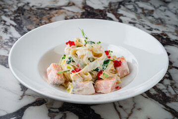 Lunch Linguini pasta with salmon, spinach, cream sauce, caviar and microgreens in a plate.