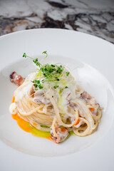 Dinner pasta with bacon, cream sauce and microgreens.