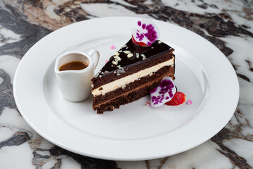 Dessert a piece of chocolate cake with vanilla cream, strawberries and caramel sauce.