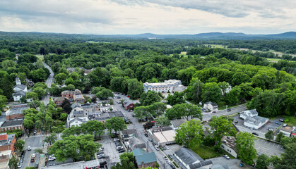 aerial view of rhinebeck new york (hudson valley small town next to catskill mountains) trees main street homes businesses houses (residential and commercial downtown area) drone looking down sunset