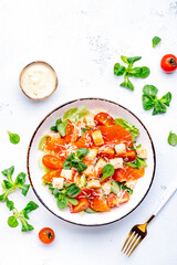 Delicious salad with salmon, iceberg lettuce, croutons, grated parmesan cheese and caesar dressing. White background, top view
