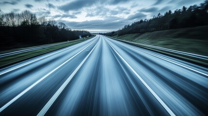 A blurred highway scene depicting a sense of speed and motion under a cloudy sky.