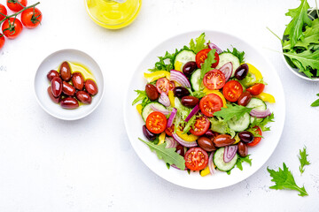 Vegan vegetable salad with olives, tomato, paprika, cucumber and onion, healthy mediterranean food. White background, top view
