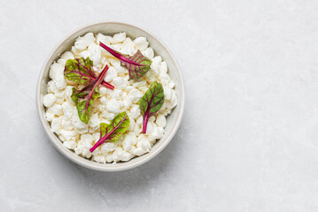 Natural cottage cheese  with fresh chard in bowl isolated on light background, top view with copy space
