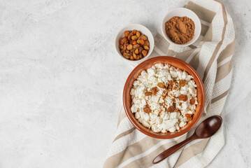 Breakfast with natural cottage cheese with raisins and cinnamon in bowl and wooden spoon top view with copy space