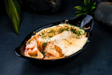 Baked thin pancakes with ham and cheese sauce in a cast-iron bowl.