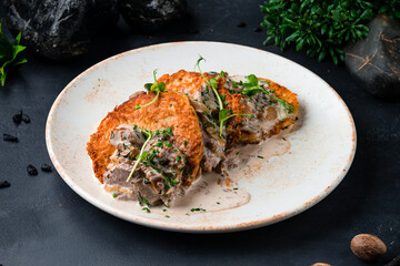 Hot draniki with beef and mushrooms in a creamy sauce.