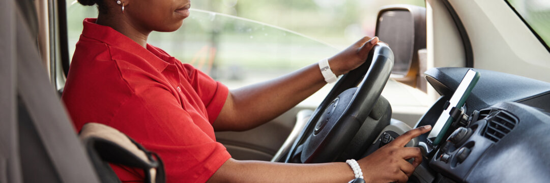 Header image with side view of unrecognizable female driver using smartphone in car