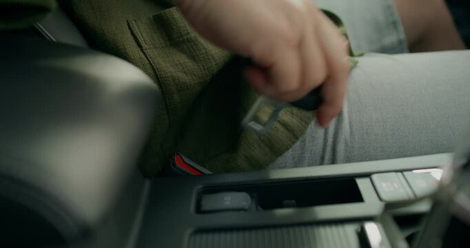 The man fastens the seat belt of the car. Close-up of the fastener and his hands, an unrecognizable person. View from the car interior.