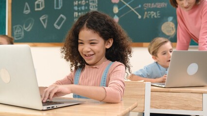 Attractive girl coding prompt while looking at camera at STEM class while happy teacher checking smart boy software program. Diverse student study about programing code and computing system. Pedagogy.