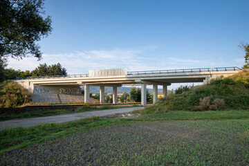 Reinforced Concrete road bridge over railway track during summer. Concrete suspension bridge surrounded by green meadows. 