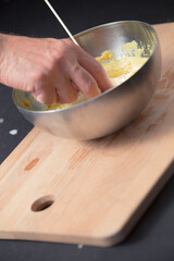 man chef hand in a metal bowl of dahl yellow lentil on wooden cutting board