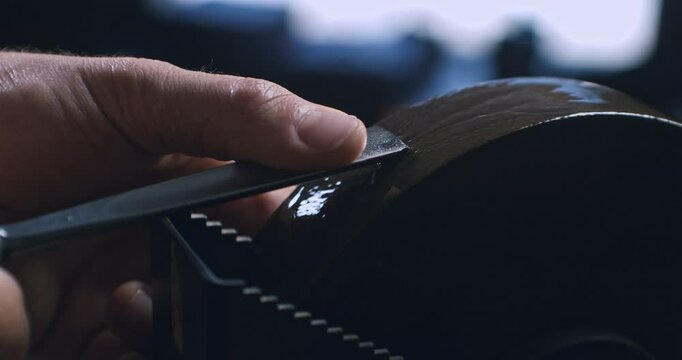 Super slow motion macro of artisan carpenter is sharpening chisel with grinder before working piece of wood for crafting wood artistic sculpting items in his workshop studio at 1000 fps.