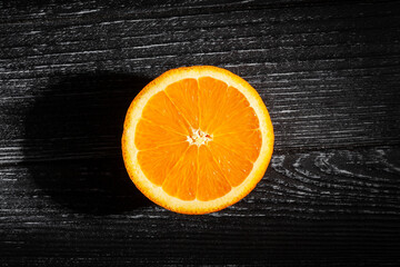 sliced oranges on black wood background top view