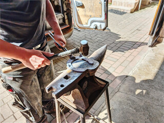 Farrier working at shoeing a horse. Blacksmith making horseshoe. A smith forging a horse shoe