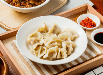Steamed Dumplings filling with cabbage and pork in bowl with chili oil and soy sauce isolated on napkin side view on table taiwan food