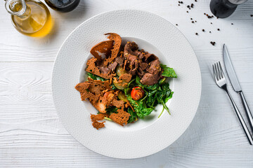Meat salad with beef slices, cherry tomatoes, zucchini, spinach, lettuce, bread and Dijon mustard.