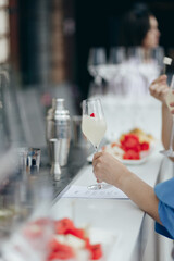 A girl takes a glass of sparkling champagne at a bar