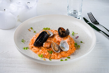 Italian lunch risotto with shrimps, vongole, mussels, parmesan cheese, sauce and microgreens.