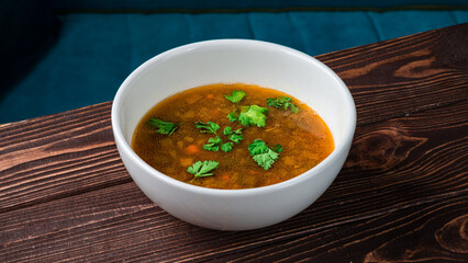 Soup with carrots, onions, potatoes, pork and parsley in a bowl.