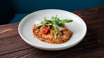 Fried breaded chicken fillet with stewed vegetables, parmesan cheese and arugula.