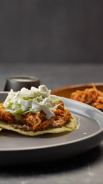 Vertical video of a pair of tinga tostadas, panned to the left in slow motion