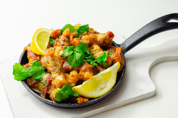 A black pan with shrimp and lemon slices