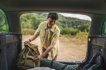 mature japanese woman take stuff for camping from the back of her car