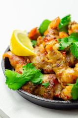 A black pan with shrimp and lemon slices