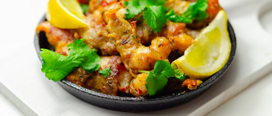 A black pan with shrimp and lemon slices