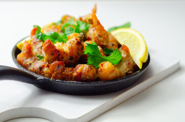 A black pan with shrimp and lemon slices