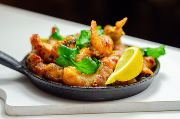 A black pan with shrimp and lemon slices