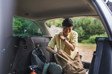 mature japanese woman take stuff for camping from the back of her car