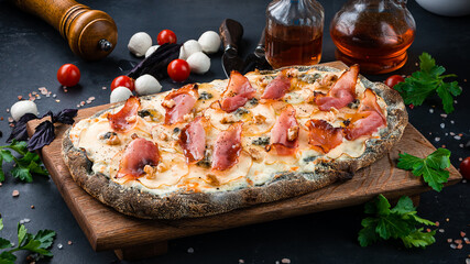 Italian lunch pinza or pizza with pear, gorgonzola cheese, bacon and walnuts on rye dough.