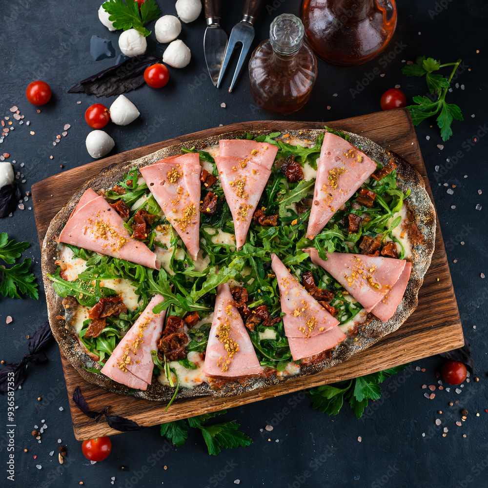 Wall mural italian cuisine pinza or pizza with ham, cheese, sun-dried tomatoes and arugula on rye dough.