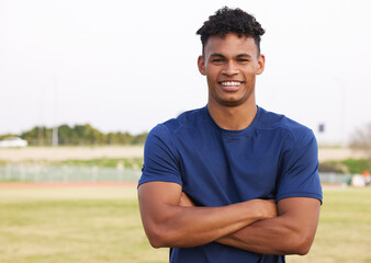 Fototapeta premium Man, arms crossed and happy for soccer in sports field with training, workout and exercise in Brazil. Male person, portrait and smile in confidence as football player for match or tournament