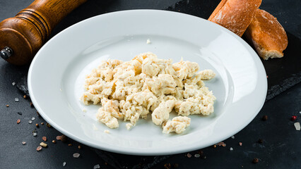 Scrambled egg omelet with bread, salt and pepper on a dark background.