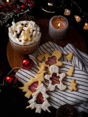 Festive hot chocolate with marshmallows and holiday cookies, adorned with Christmas decorations, warm candlelight setting.