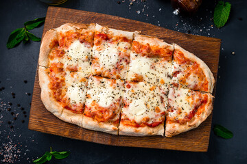 Italian food pizza with mozzarella, tomato sauce, spinach with spices on a wooden board.