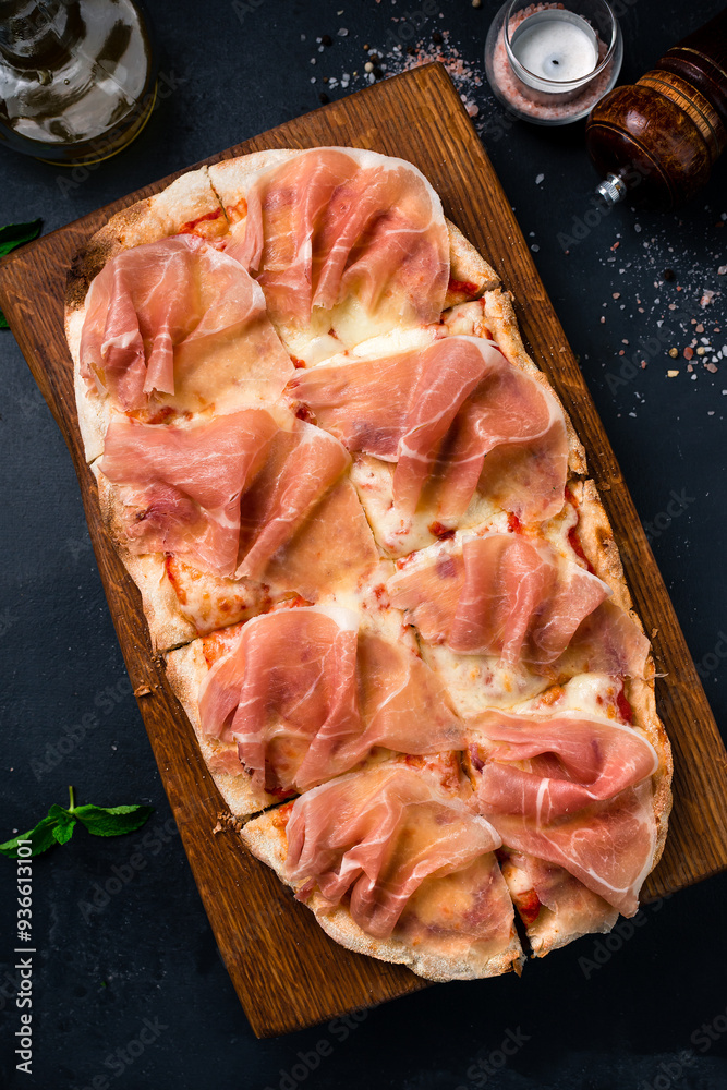 Wall mural pizza with ham, cheese and tomato sauce on a wooden board.