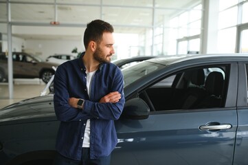 Young man is choosing a new vehicle in car dealership