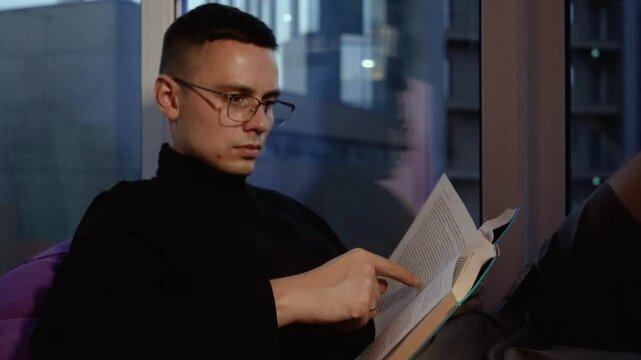 Handsome businessman man reading a book at home in a business center to become even more successful. Smart man who is engaged in self-development and learning his skills
