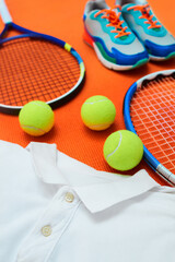 Ball, racket and clothes in studio for tennis competition, match or fitness challenge at health club. Sports, shoes and exercise gear on court for international games, workout and orange background