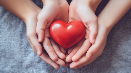 Two hands holding a red heart-shaped object, symbolizing love and compassion in a warm, inviting atmosphere, suitable for various contexts like Valentine's Day or charity