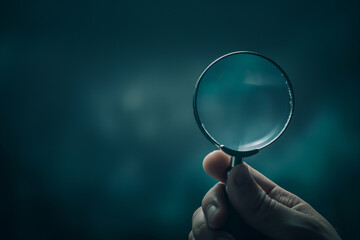 Hand Holding Magnifying Glass on Teal Background