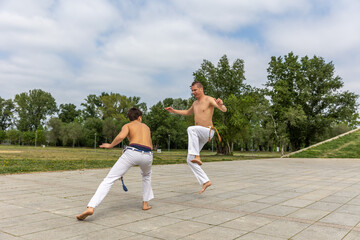 Teenager and middle aged man practicing capoeira , brazilian martial art