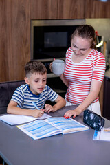Mother helping son with homework in kitchen at home