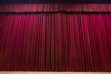 Red curtain on a theater stage, showing the base and the wavy fabric.