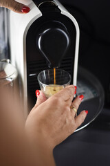 CHICA HACIENDO UN CAFE EN UNA CAFETERA DE CAPSULAS